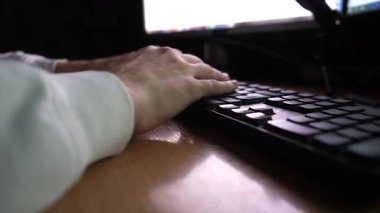 Erkek parmaklar akşamları bilgisayar klavyesinde yazı yazıyor. Genç adamın kolları iş yerindeki bilgisayarla bilgi girişi yapıyor. Masaüstünde yeni bir projede çalışan adam. Bağımsız iş kavramı. Yavaş çekim.