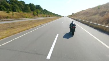 Bisikletçi yaz günü yol gezisi sırasında motosiklet sürüyor. Adam otoyolda modern spor motosikletle hızlı gidiyor. Motosikletli, kır yolunda bisikletiyle yarışıyor. Macera kavramı. Hava görüntüsü.