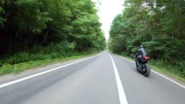 Motosikletli, ormanda araba gezisi sırasında motosiklet sürüyor. Orman yolunda, modern spor motosikletli bir adam. Motosikletli kırsal yolda bisikletiyle yarışıyor. Macera kavramı. Hava görüntüsü.