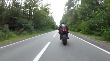 Motorcu, boş köy yolunda motorsikletle hızlanıyor. Orman yolunda, modern motorsikletle hızlı giden bir adam. Yolculuk sırasında bisiklet süren adam. Özgürlük ve macera kavramı. Hava görüntüsü.