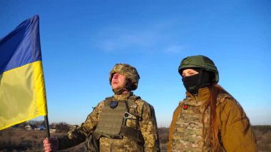 Ukrayna bayrağı sallayan Ukrayna ordusunun askerleri. Üniformalı askerler mavi gökyüzüne bayrak kaldırdı. Rus saldırısına karşı zafer. İstila direnci konsepti. Yavaş çekim.