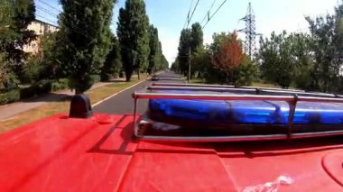 Şehir yolundaki yangın yerine giderken mavi ışıklı büyük kırmızı bir kamyonet. İtfaiye aracı şehir caddesinde acil durum yerine gidiyor. Hayat kurtarmak ve kahramanlık mesleği kavramı. Üst görünüm.