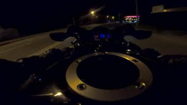 Akşamları yüksek hızda motosiklet kullanan motosiklet sürücüsünün bakış açısı. Aydınlanmış şehir sokaklarında modern spor bisikleti süren erkek motosikletçi. Özgürlük kavramı. POV