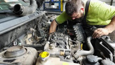 Erkek tamirci garajda arabanın bakımını yapıyor. Yetişkin oto tamircisi atölyede aracın kaputunun altında çalışıyor. İş yerinde otomobil teftişi yapan profesyonel bir tamirci. Aktarım tanısı.