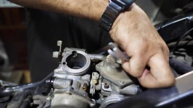 Tamircinin erkek elleri, işyerindeki aletleri kullanarak motorun motorunu tamir ediyor. Atölyede motor tamir eden profesyonel tamirci kolları. Garajda çalışan yetişkin bir tamirci. Yavaş çekim.