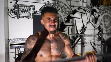 Kaslı Afro-Amerikan sporcusu modern spor salonunda yoğun halter kıvrımı egzersizleri yapıyor. Atletik siyahi adam spor kulübünde sıkı çalışıyor. Fitness merkezinde Afrikalı sporcu eğitimi. Kapat..