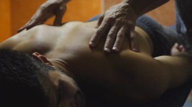 Salondaki sporcunun omuzlarına masaj yapan profesyonel masörlerin ellerine yakın. Masajcının erkek kolları, kuafördeki genç atlete masaj yapıyor. Sağlıklı yaşam tarzı kavramı.