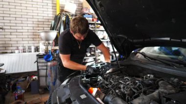 Servis kaputu altında çalışan profesyonel bir tamirci. Genç oto tamircisi atölyedeki arabanın motorunu tamir ediyor. Erkek tamirci garajdaki otomobil motorunu kontrol ediyor. Taşıma tanısı konsepti.