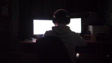 Erkek oyuncu evdeki bilgisayarda birinci şahıs nişancı olarak oynuyor. Kulaklıklı genç adam geceleri bilgisayar başında online video oyunu oynuyor. Siber uzay, rekabet ve turnuva kavramı. Yavaş çekim.