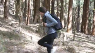 Kadın backpacker yaz tatili seyahat sırasında ahşap geçiyor. Ormanda yürüyen sırt çantası ile genç kadın turist. Doğada yürüyüş kız. Sağlıklı aktif yaşam tarzı kavramı. Yan görünüm.