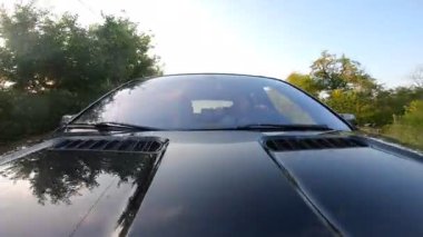 Genç çift kırsalda araba sürmekten zevk alıyor. Erkek arkadaş ve kız arkadaş gün batımında otomobille seyahat ediyorlar. Yolculuk kavramı. Ön görünümü kapat.