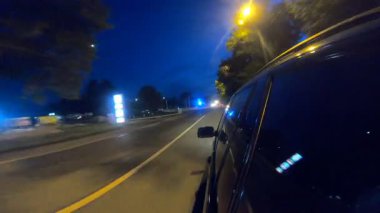 Geceleri kırsal yolda yarışan siyah jipin görüntüsü. Akşamları otomobille yola çıkıyoruz. Araç otoyol boyunca kırsal alanlardan hızla geçiyor. Trip ya da seyahat konsepti. POV.