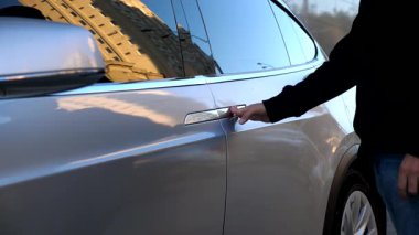 Modern elektrikli cip arabasının arka kapısını erkek el açıyor. Elektrikli otomobilin kapısını açmak için düğmeye basan adam. Çağdaş teknolojiler kavramı. Yavaşça kapat..