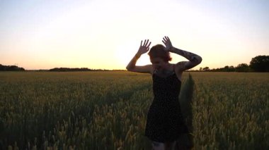Kısa siyah elbiseli neşeli punk kızı buğday çayırlarında dolaşırken aylaklık ediyor. Dövmeli mutlu bayan hippi gün batımında yeşil arpa tarlasından geçiyor. Özgürlük kavramı.