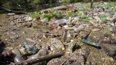 Nehir birçok plastik şişeyle kirlidir. Pek çok çöp doğadaki açık ve serbestçe ulaşılabilir yerlere atılır. Küresel çevre kirliliği sorunu. Ekolojik felaket kavramı.