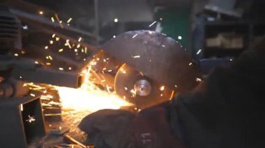 Metal öğüten profesyonel işçilerin elleri. Endüstriyel imalatta çelik testeresi. Birçok parlak kıvılcım sıcak metalden uçar. Garajdaki kesim makinesini gördüm. Yavaş çekim. Yakın çekim..