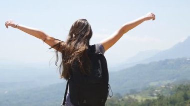 Dişi yürüyüşçü dağın tepesine ulaşır ve kollarını uzatır. Sırt çantalı kadın turist kanyonun kenarında duruyor ve ellerini kaldırıyor. Genç gezgin güzel manzaranın tadını çıkarıyor..