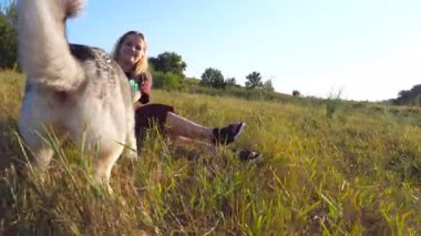 Sarışın bir kızın elinde plastik bir şişe tutarken Sibiryalı kurt ısırıp doğayı çekiştirirken çekilen Dolly 'nin fotoğrafı. Sahada köpekle vakit geçiren mutlu bir kadın. Düşük açı görünümü.