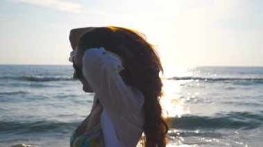 Güzel kız bikini ve sahil yürüyüş ve saçları ile oynarken gömlek portresi. Mutlu genç kadın gülümseyerek ve yaz tatili hayattan zevk güneş gözlüğü. Ağır çekim yakın çekim.