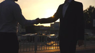 Takım elbiseli bir erkek arkadaşının anahtarlarını veriyor. İş adamının kolu arabanın anahtarını verir. İki iş adamı arasında el sıkışma. Yavaşça kapat..