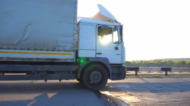 Kamera otoyolda giden kamyonu takip ediyor. Kamyon arka planda güzel bir manzarayla kırsal alanda geziniyor. Asfaltta kamyon gezintisi. Sürücü yüksek hızda sürüyor. Yan Görünüm Kapat.