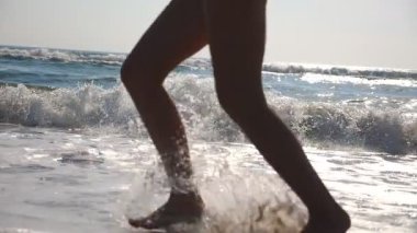 Arka plan dalgalar ile plajda ıslak kum ve deniz suyu çalışan kadın ayak kapatın. Kıyıda çalışan genç kadının bacakları. Sahil yalınayak kıza. Yaz tatil tatil. Ağır çekim.