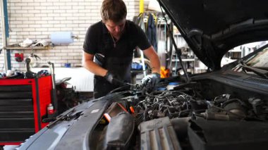 Servis kaputu altında çalışan profesyonel bir tamirci. Genç oto tamircisi atölyedeki arabanın motorunu tamir ediyor. Erkek tamirci garajdaki otomobil motorunu kontrol ediyor. Taşıma tanısı konsepti.