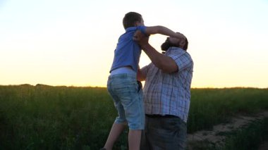 Mutlu baba, neşeli oğlunu kırsala kusuyor. Baba ve küçük çocuğu gün batımında doğada eğleniyorlar. Babası ve küçük oğlu dışarıda birlikte vakit geçiriyorlar. Aile mutluluğu kavramı.