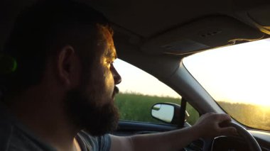 Sakallı, taşrada araba kullanan kendine güvenen bir adamın profili. Araba sürerken yola odaklanmış ciddi bir erkek sürücünün yüzünü kapatın. Yolculuk ve seyahat kavramı. Yavaş çekim.