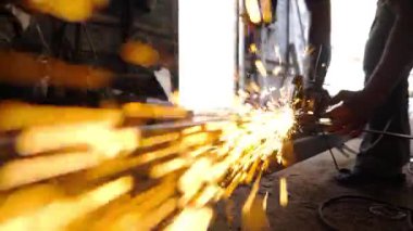 Genç zanaatkarın erkek elleri atölyede elektrikli öğütme çarkını kullanarak demir kesiyor. Garajda ya da işyerinde metal testeresi kullanan profesyonel tamirci kolları. Yavaş çekim.