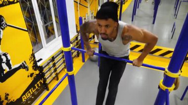 Modern spor salonundaki yatay barda egzersiz yapan güçlü bir Afrikalı atlet. Kaslı Afro-Amerikan sporcusu içeride çalışıyor. Genç siyahi adam fitness kulübünde antrenman yapıyor. Sportif aktif yaşam tarzı.