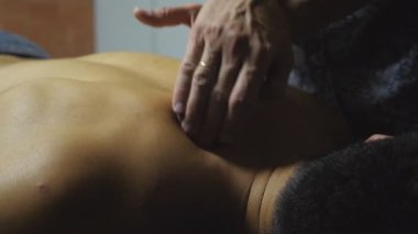 Profesyonel masörün erkek ellerine yakın. Salondaki kaslı sporcunun omuzlarına masaj yapıyor. Masajcı, kuafördeki genç atlete masaj yapıyor. Sağlıklı yaşam tarzı kavramı.