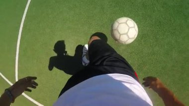 Atletik alandaki bireyler, spor yaparken dinamik ayak hareketlerini ve kontrollerini sergileyerek, hareket ve tekniği vurgulayarak, canlı yeşil bir sahada ustalıkla top sürme becerisine sahipler.