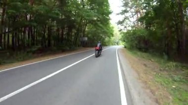 Motosikletli, ormanda araba gezisi sırasında motosiklet sürüyor. Orman yolunda, modern spor motosikletli bir adam. Motosikletli kırsal yolda bisikletiyle yarışıyor. Macera kavramı. Hava görüntüsü