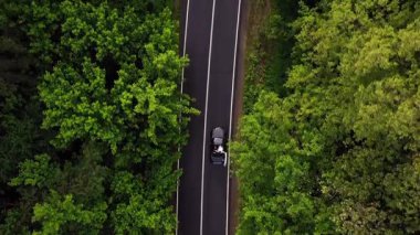 Hava perspektifi, dolambaçlı bir yolda, canlı yeşilliklerle kaplanmış, dinamik yolculuğu resmeden, dinamik doğal bir çevreyi gösteren bir araba yakalar.