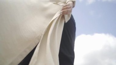 Açık renkli bir elbisenin dalgalanan kumaşı figürün ilerleyişi, hareketin özünü ve sakin açık hava atmosferini yansıtıyor.