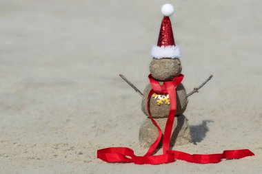 Kumsalda Noel Baba şapkalı Sandy Kardan Adam. Yılbaşı ve Noel kartları için tatil kavramı.