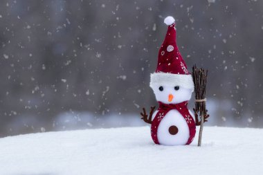 Kardan adamın olduğu bir Noel arkaplanı. Elinde süpürgeyle Noel Baba şapkalı komik bir kardan adam. Kış konsepti..