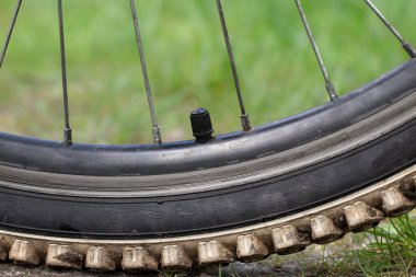Kapalı bisiklet tekerleği hava vanası. Yazın yeşil çimlerde bisiklet tekerinin meme ucuna yakın çekim. Lastik patlamış..