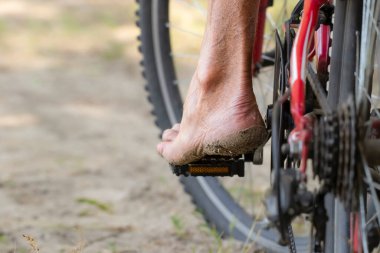 Bisiklet pedalına basmak. Bisiklet pedalında ayakkabısız erkek ayağı. Aktif yaz..