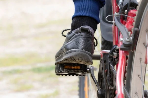 A cyclist\'s foot on a pedal, a close-up.A man\'s foot in a sneaker on a bicycle pedal.The concept of cycling, cycling.