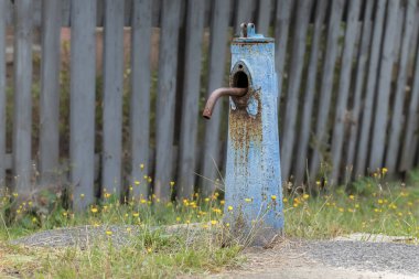 Köyde mavi çatlamış boyalı eski bir su sütunu. İçme suyu tedarik sütununa yakın çekim.