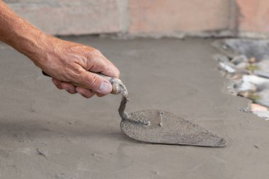 Bahçe yolunun betonlaşması. Bir adam çimento karışımını trowell ile elle dağıtıyor. Bahçede iş yapıyor..