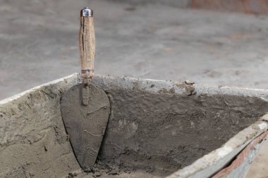 Bahçe yolunun betonlaşması. Bir adam çimento karışımını trowell ile elle dağıtıyor. Bahçede iş yapıyor..