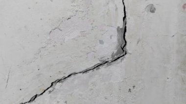 Eski duvarda çatlamış beton zemin kötü inşaat veya deprem yüzünden kırılmış.