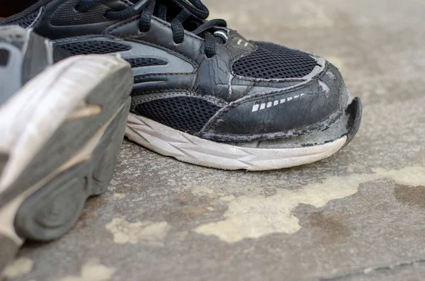 破了的旧黑运动鞋在地板上 — 图库照片
