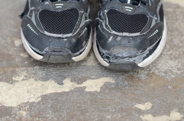 地板上破了的旧黑运动鞋 — 图库照片