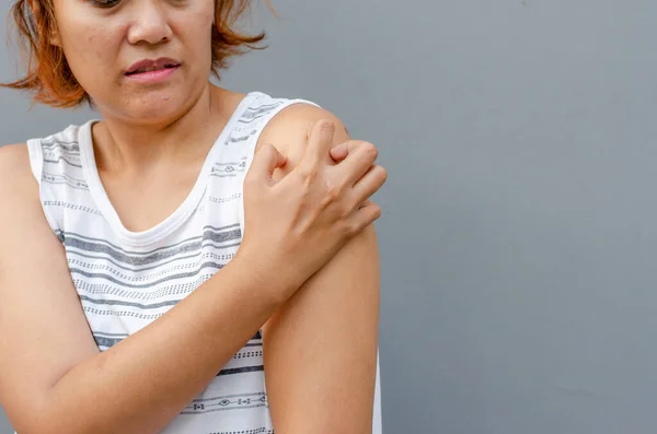 stock image young asian woman scratching itch with hand on upper arm or shoulder area, health care concept