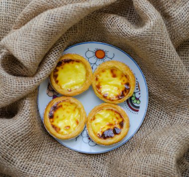 Yuvarlak tabakta ev yapımı yumurtalı tartlar, tatlı. kahverengi kumaş arka planında
