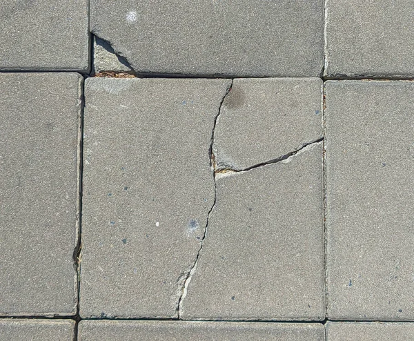 Broken concrete footpaths brick surface background. close up cracked cement block texture